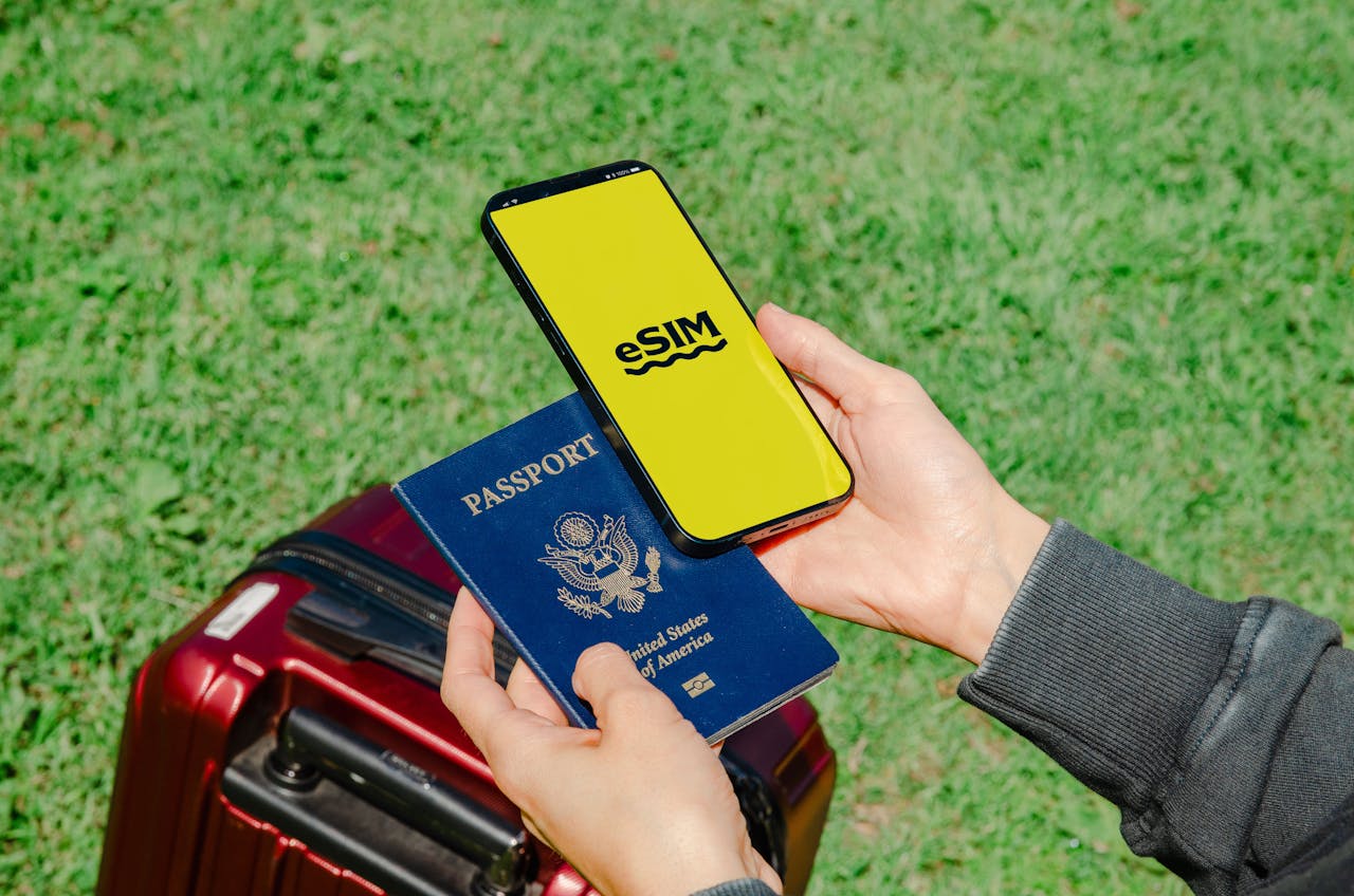 brand-01 Hands holding a smartphone with eSIM and a passport near a luggage outdoors, ideal for travel concepts.