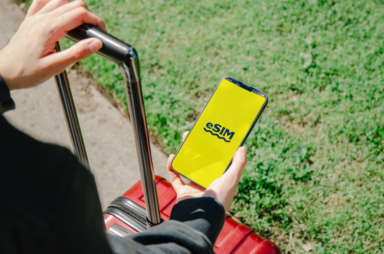 digital A person holds a smartphone showing an eSIM app while standing with luggage outdoors in Los Angeles.