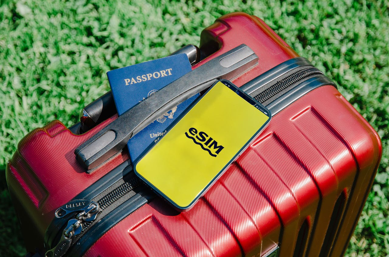 brand-02 Close-up of a red suitcase with a smartphone displaying eSIM and a passport, symbolizing travel readiness.