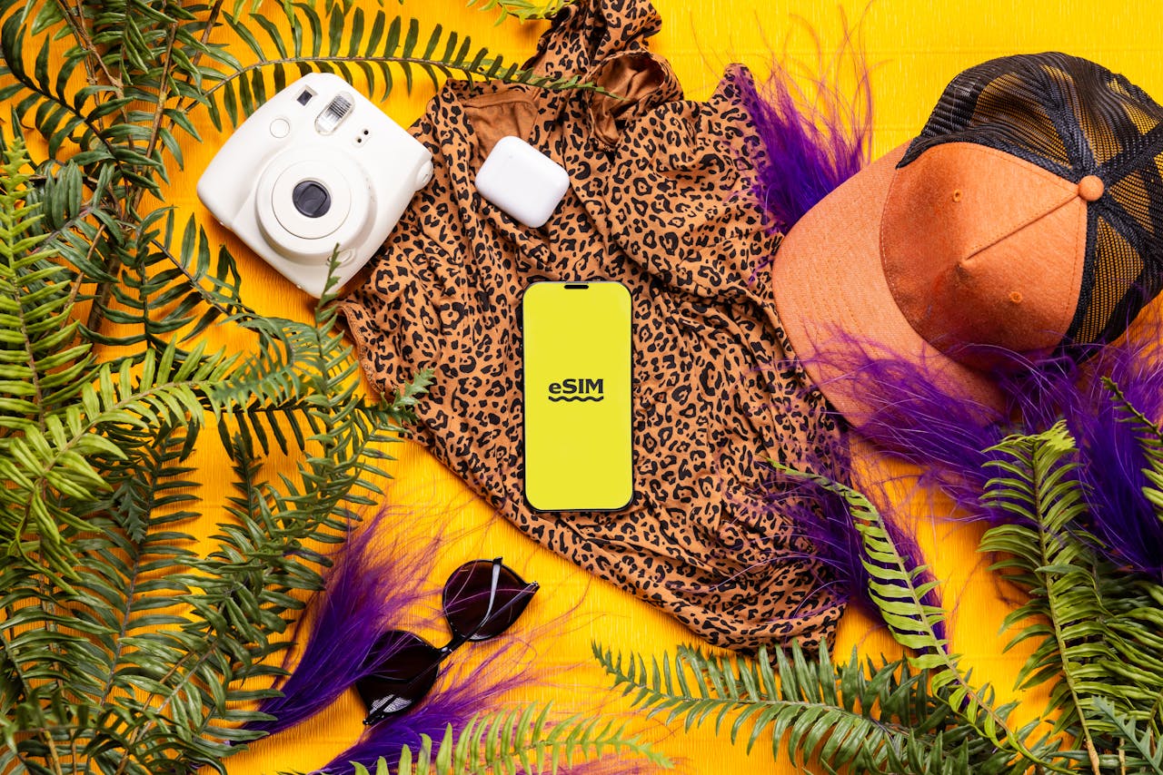 Services-02 Flat lay of summer travel essentials featuring a leopard print dress, gadgets, and greenery on a bright yellow background.