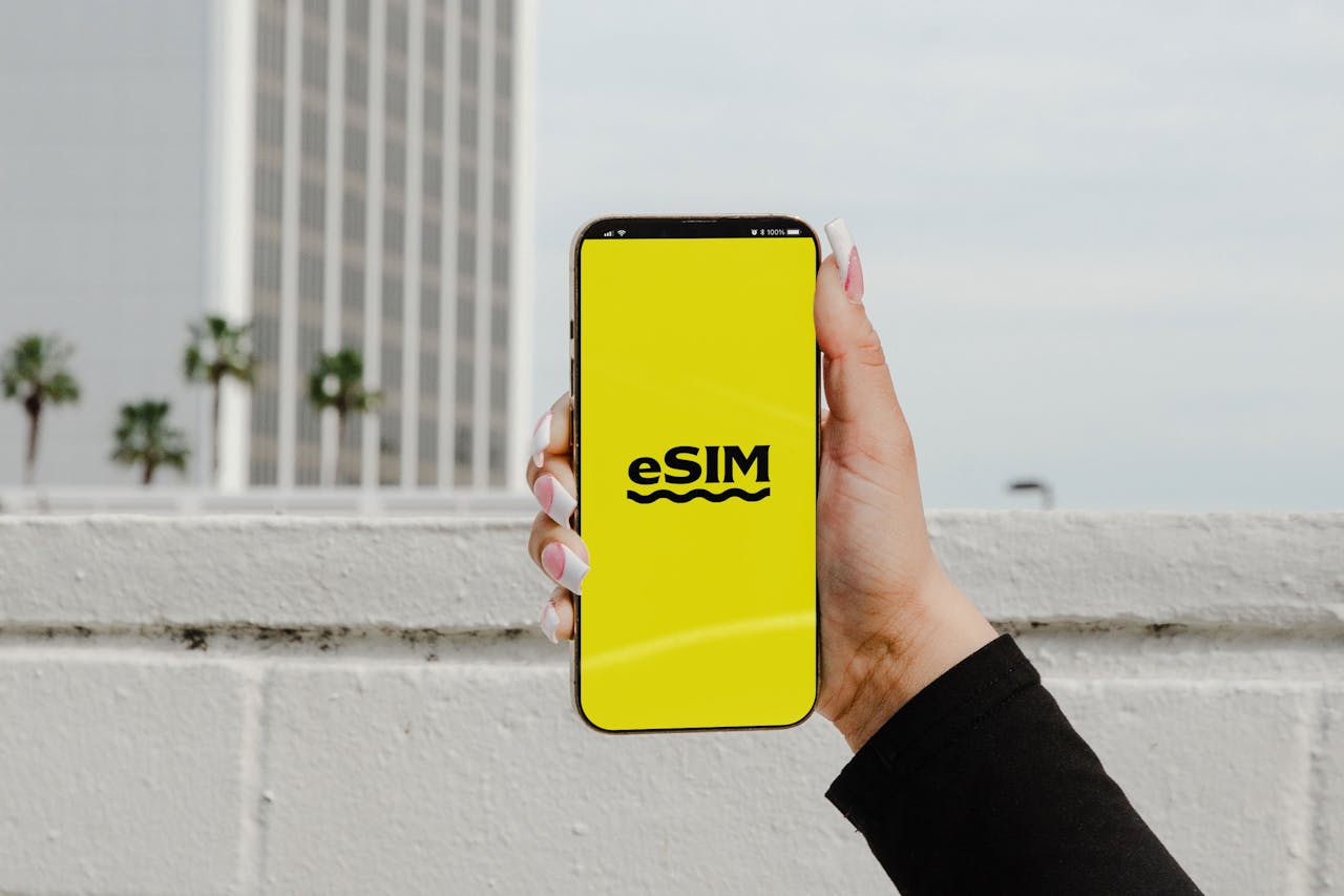 why-choose-us A hand holding a smartphone displaying eSIM against an urban backdrop in Los Angeles.